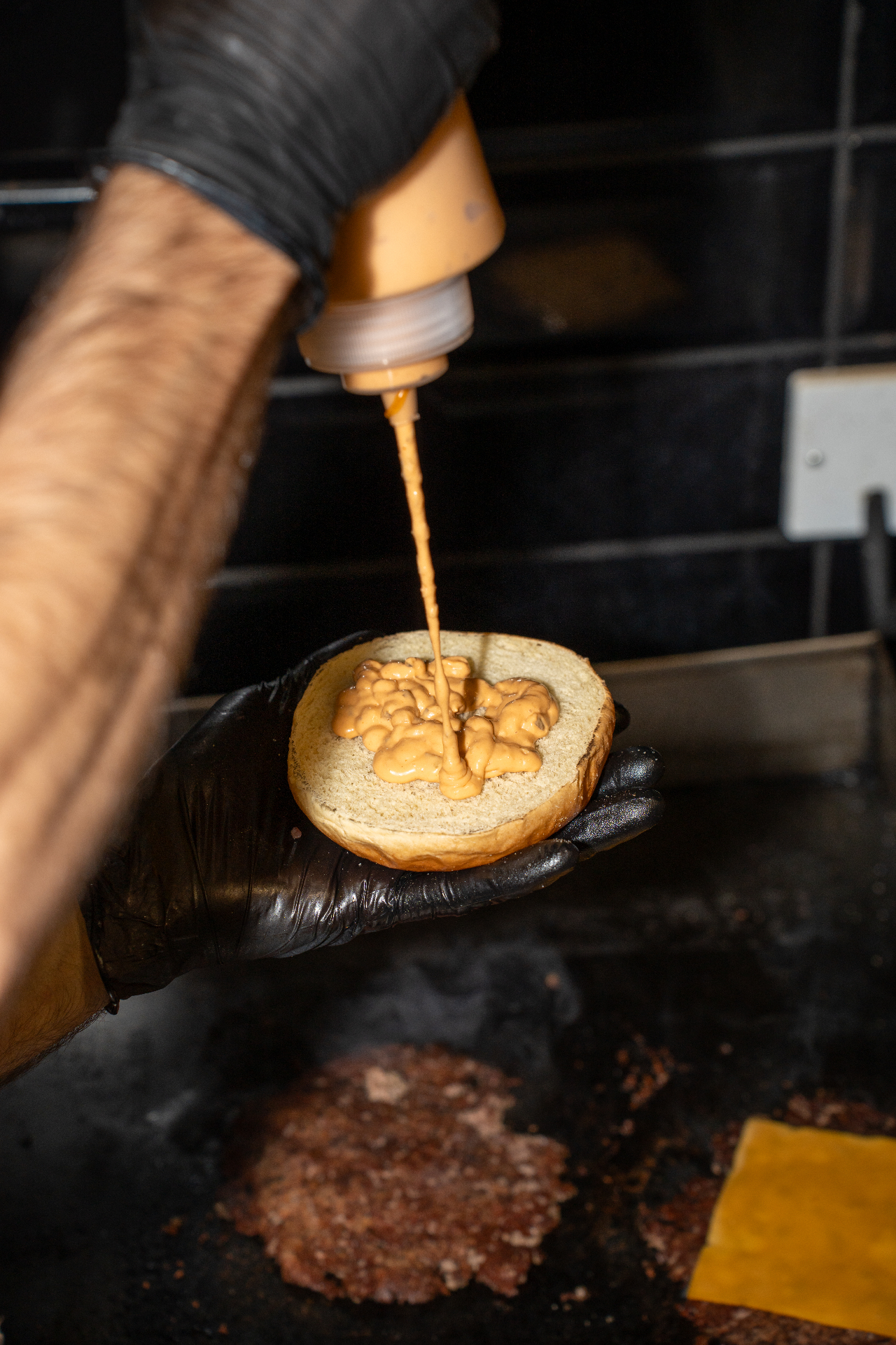 House burgerάκι sauce being poured onto a freshly toasted bun